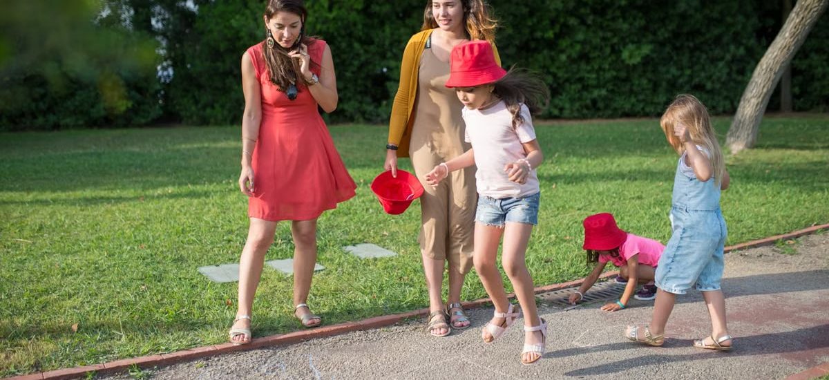 A joyous family experience in a lush Portugal park, featuring playful activities between young girls and adults.