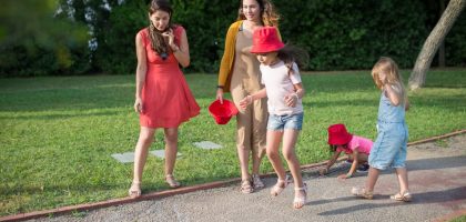 A joyous family experience in a lush Portugal park, featuring playful activities between young girls and adults.