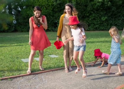 A joyous family experience in a lush Portugal park, featuring playful activities between young girls and adults.